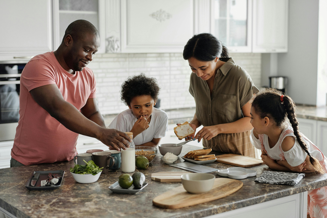 Familia desayunando alrededor de una isla de cocina. dos adultos y dos niños